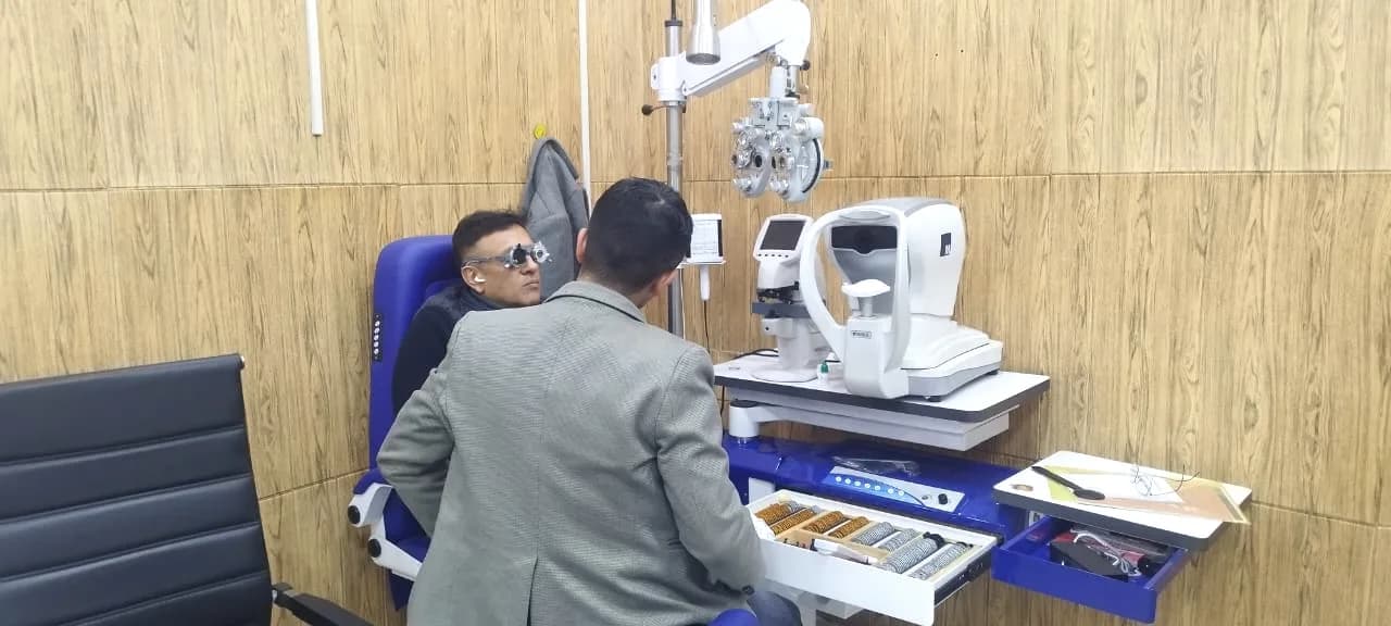 A patient in trial frames in the refraction room, with the phoropter, auto-refractor and trial lens set alongside